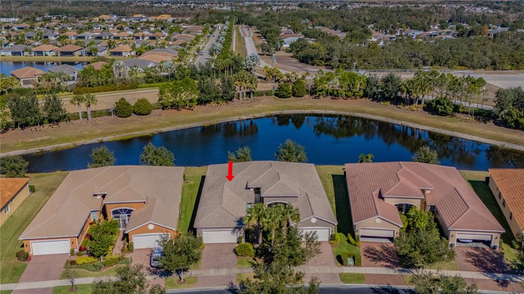 An aerial view shows a row of suburban houses situated along a pond — 15644 AURORA LAKE CIRCLE, WIMAUMA, FL