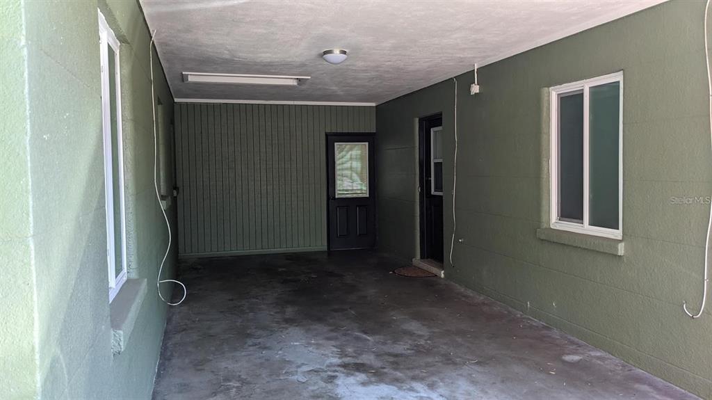 A covered carport with olive green walls, two doors, and two windows — 2104 PALM TERRACE, SARASOTA, FL
