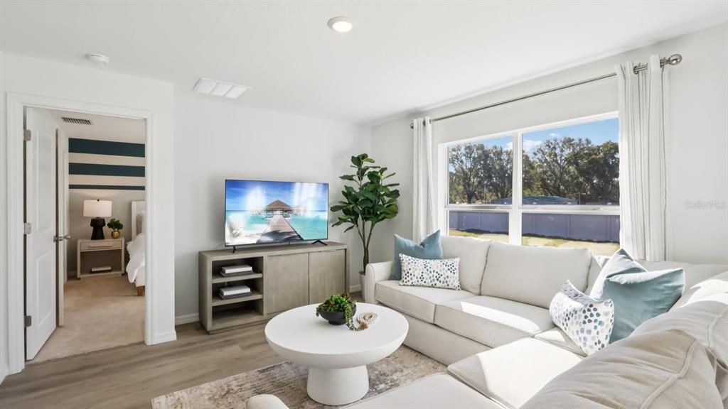 A living room features a white sectional sofa, a round coffee table, and a television — 15022 CROSSHALL STREAM DRIVE, WIMAUMA, FL