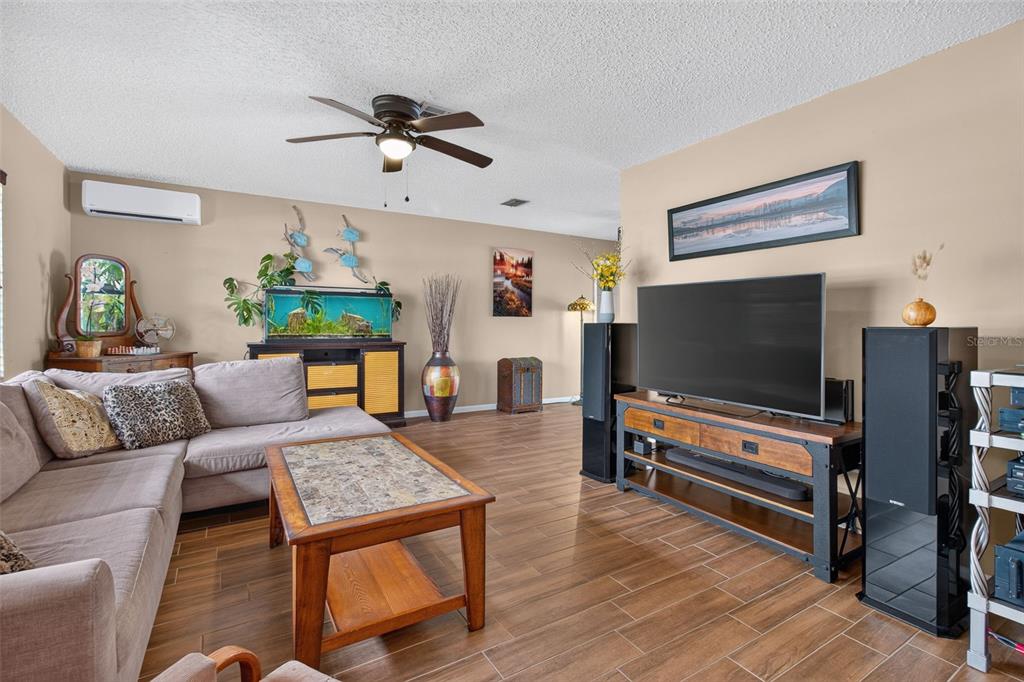 A living room features a sectional sofa, a television on a media console, and tile flooring — 2221 COLONIAL DRIVE, DUNEDIN, FL