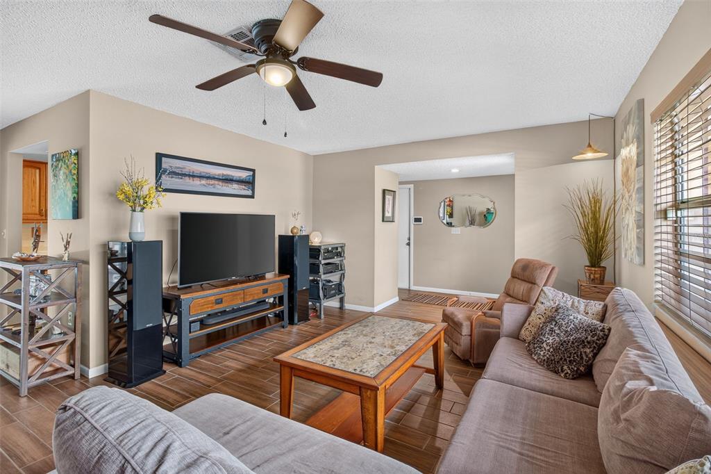 A living room features a ceiling fan, a television on a media console, and tile flooring — 2221 COLONIAL DRIVE, DUNEDIN, FL