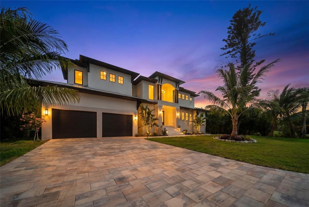 A two-story house with a paved driveway, two-car garage, and palm trees at twilight — 626 BUTTONWOOD DRIVE, LONGBOAT KEY, FL
