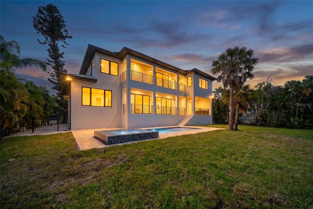 A three-story house with balconies, a swimming pool, and a hot tub at dusk — 626 BUTTONWOOD DRIVE, LONGBOAT KEY, FL
