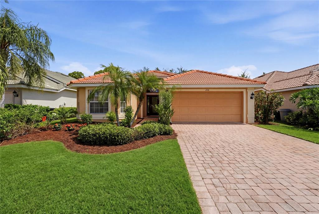 A single-story house with a tiled roof, beige stucco exterior, and a paved driveway — 2156 MESIC HAMMOCK WAY, VENICE, FL