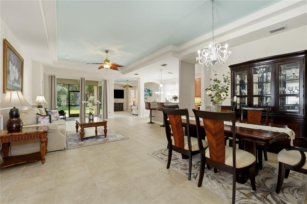 A dining and living area with tile floors, a tray ceiling, and a dark wood hutch — 2156 MESIC HAMMOCK WAY, VENICE, FL