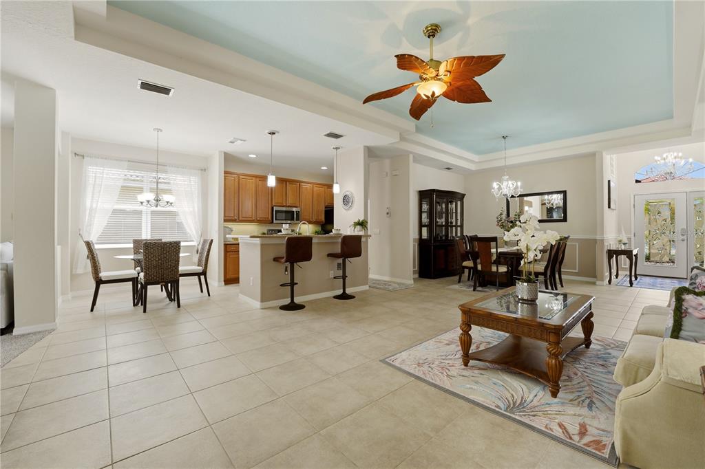 An open-concept living and dining area features tile floors, a tray ceiling, and wooden cabinetry — 2156 MESIC HAMMOCK WAY, VENICE, FL