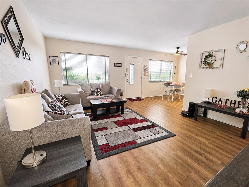 A living room features light wood flooring, a gray sofa, and a geometric area rug — 11251 80TH AVENUE UNIT 306, SEMINOLE, FL