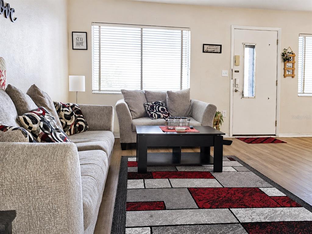 A living room features gray sofas, a black coffee table, and a geometric area rug — 11251 80TH AVENUE UNIT 306, SEMINOLE, FL