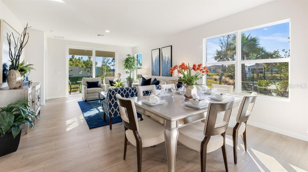 A dining area with a silver table and chairs opens into a bright living room — 4583 SCHUBERT TRAIL, NORTH PORT, FL