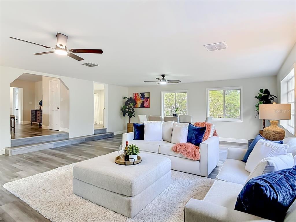 A living room features white sofas, a large ottoman, and gray wood-look flooring — 265 NEWCOMB STREET, NEW SMYRNA BEACH, FL