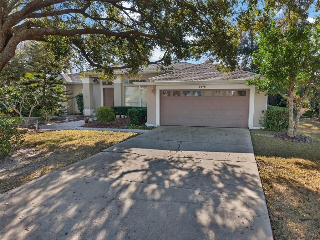 A single-story house with a beige exterior, a two-car garage, and a concrete driveway — 4478 PRO AM AVENUE E, BRADENTON, FL