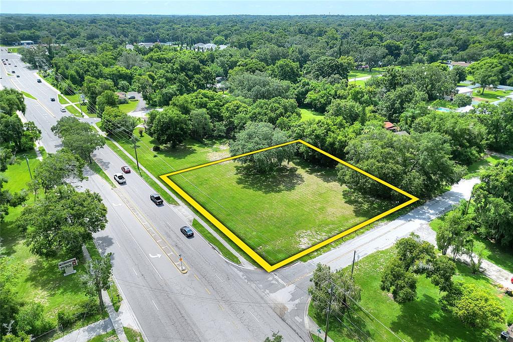 An aerial view shows a vacant, rectangular grassy lot outlined in yellow beside a road — 703 E LUMSDEN ROAD, BRANDON, FL