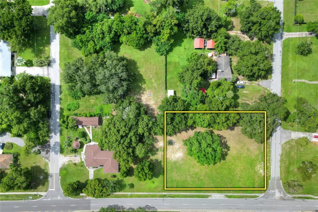 An aerial view shows a rectangular, grassy vacant lot highlighted by a yellow border — 703 E LUMSDEN ROAD, BRANDON, FL