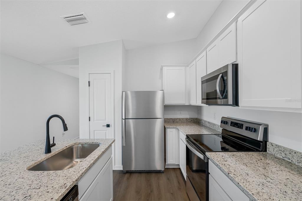 A kitchen features white cabinets, granite countertops, stainless steel appliances, and a kitchen island — 5269 CAP ROAD, BROOKSVILLE, FL