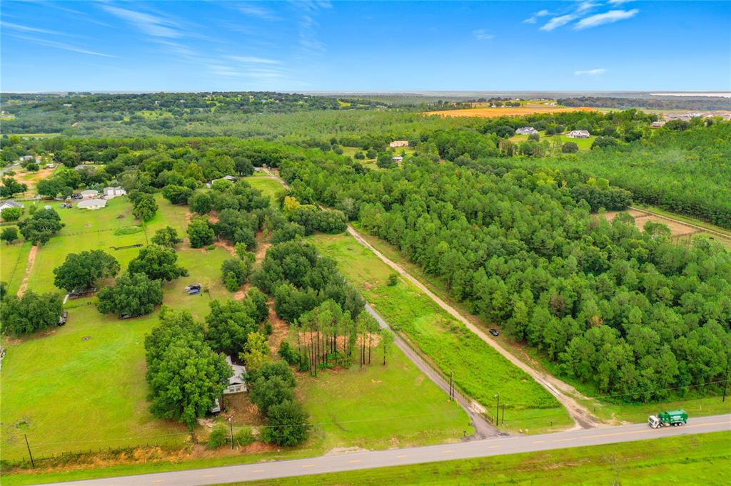 An aerial view shows a rural property with a house, trees, and a dirt driveway — 13131 COUNTY ROAD 561A, CLERMONT, FL