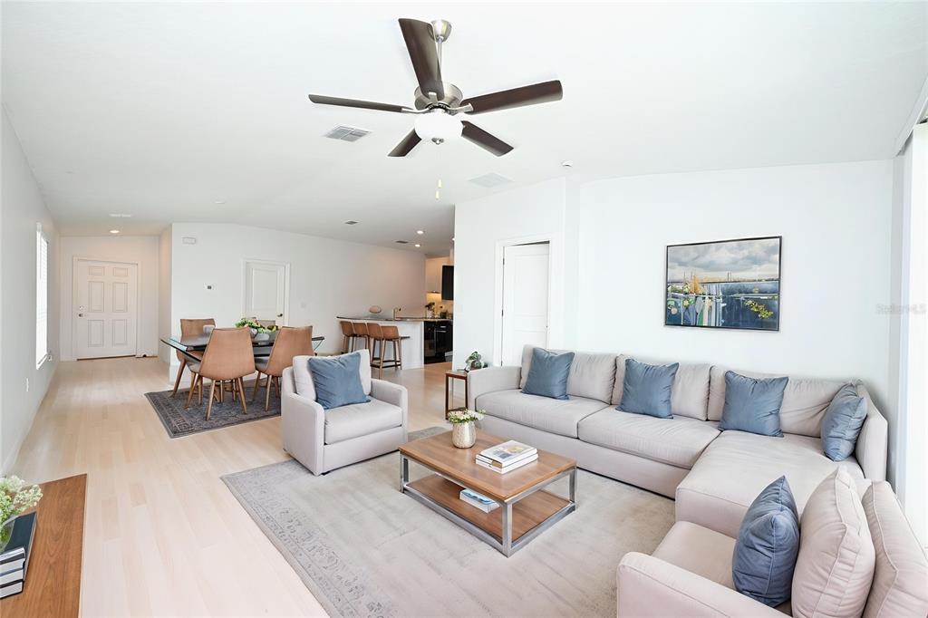 An open-concept living and dining area features light wood flooring, a ceiling fan, and furniture — 2674 RED EGRET DRIVE, BARTOW, FL