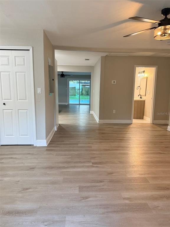 An interior view shows light wood-look flooring, a ceiling fan, and a doorway to a bathroom — 1217 E NORFOLK STREET, TAMPA, FL