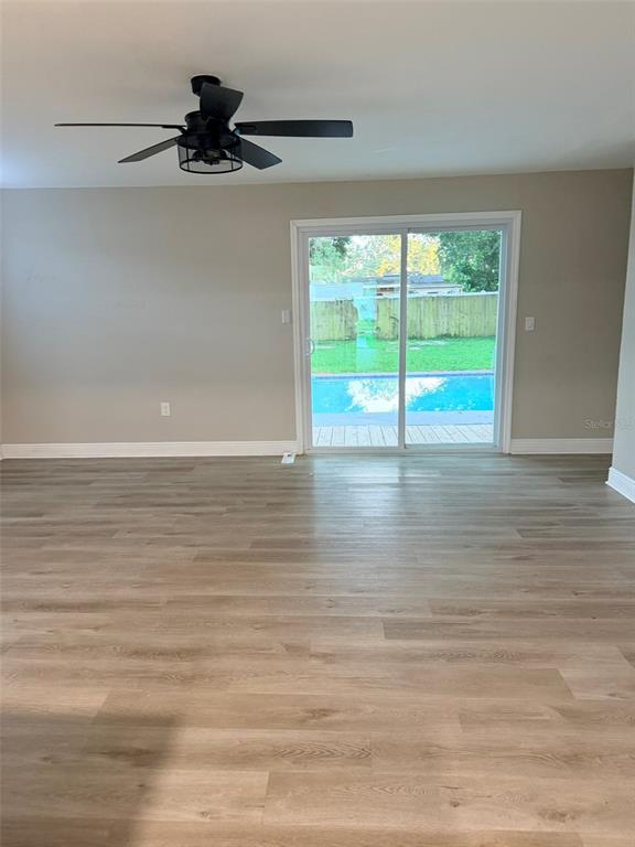 A room with light wood-look flooring, a ceiling fan, and sliding doors overlooking a pool — 1217 E NORFOLK STREET, TAMPA, FL