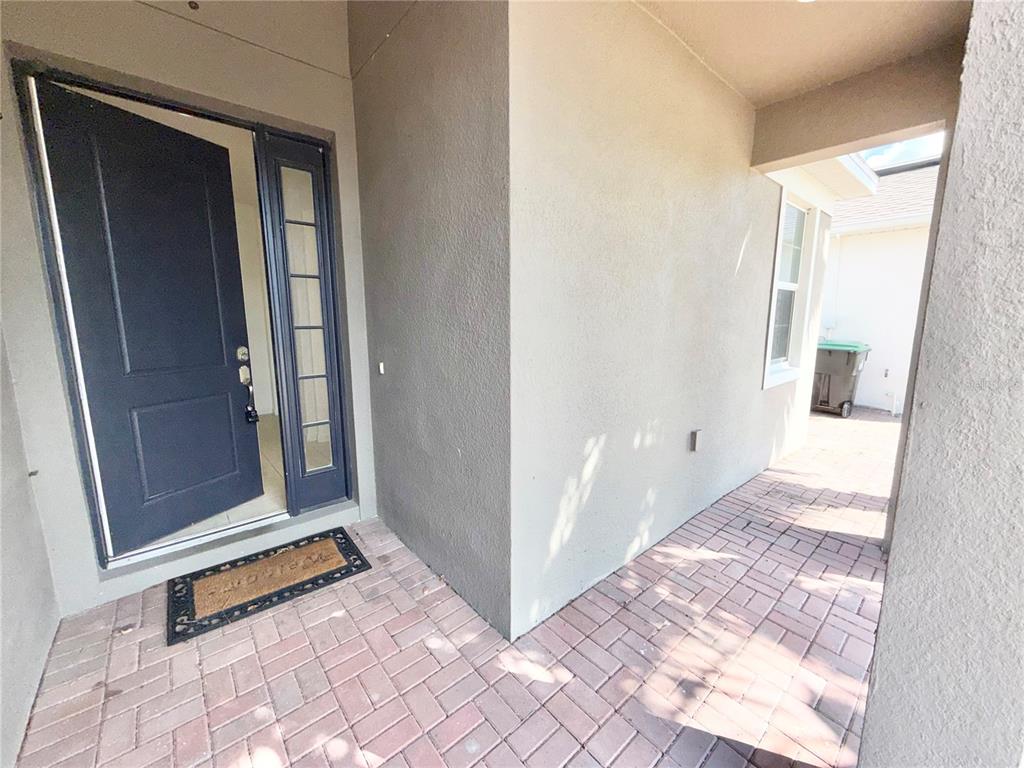 A dark front door with a sidelight opens onto a paved entryway with beige walls — 2240 RUSH BAY WAY, ORLANDO, FL