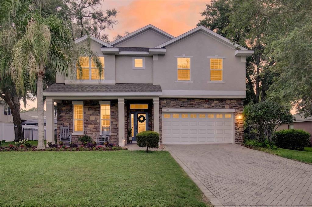 A two-story house with a stone facade, a paved driveway, and a front porch — 303 W BLUE WATER EDGE DRIVE, EUSTIS, FL