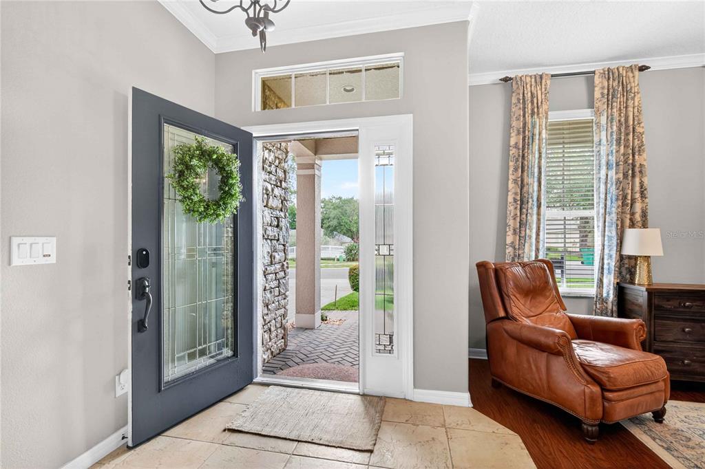 An entryway features a dark gray front door, tile flooring, and a leather armchair — 303 W BLUE WATER EDGE DRIVE, EUSTIS, FL