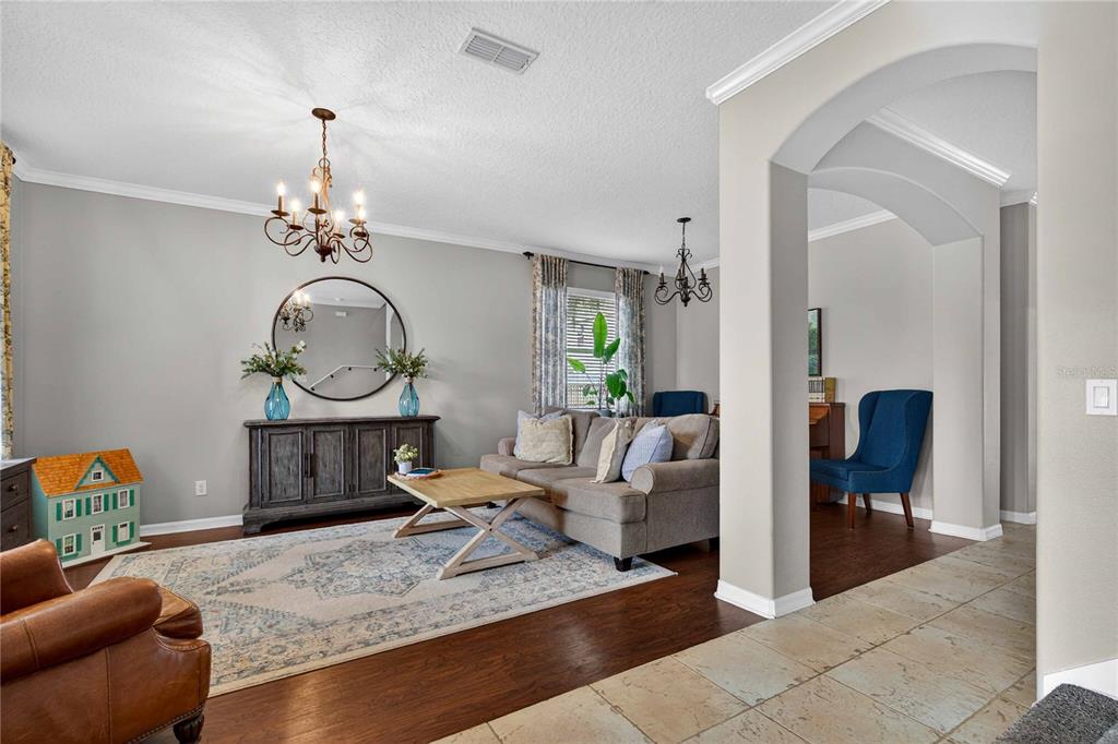 A living room features a gray sofa, a wooden coffee table, and a round mirror — 303 W BLUE WATER EDGE DRIVE, EUSTIS, FL