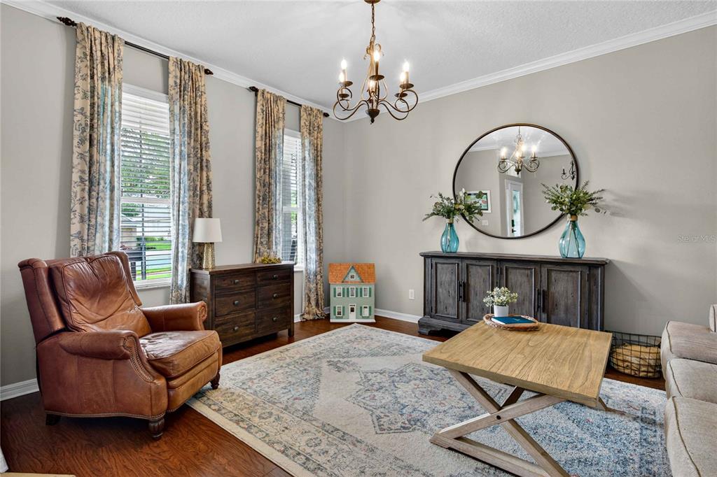 A living room features a leather armchair, a wooden sideboard, and a large round mirror — 303 W BLUE WATER EDGE DRIVE, EUSTIS, FL