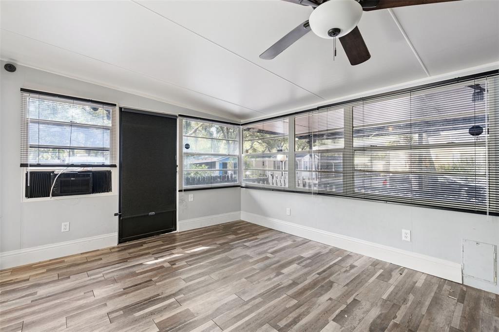 A sunroom features light gray walls, wood-look flooring, a ceiling fan, and multiple windows — 3000 CLARCONA ROAD UNIT 767, APOPKA, FL