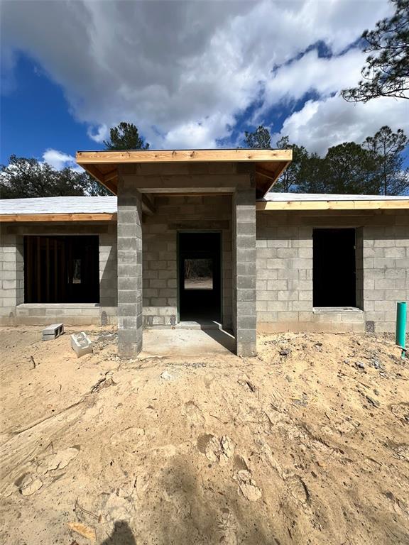 The exterior of a house under construction features concrete block walls and a covered entryway — 3 GUAVA PASS RUN, OCKLAWAHA, FL