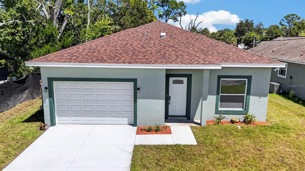 A single-story house with a light green exterior, a white garage door, and a shingled roof — 757 INDIANA STREET, DAYTONA BEACH, FL
