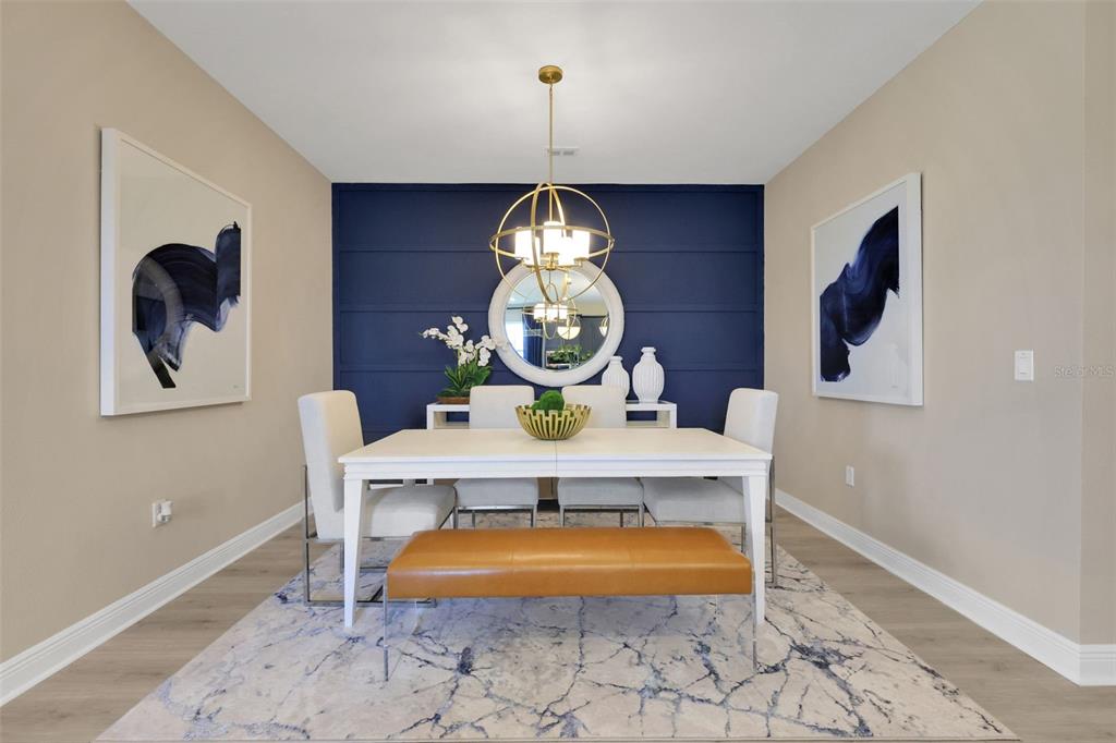 A dining room features a navy blue accent wall, a white table, and a gold chandelier — 17338 WILD DAISY DRIVE, WINTER GARDEN, FL