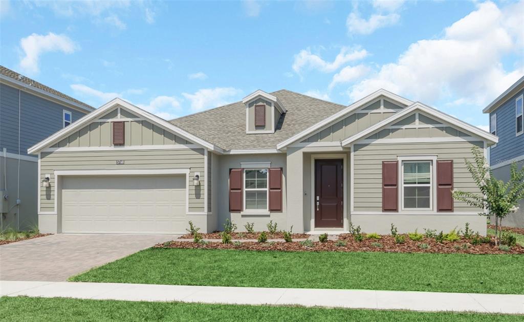 A single-story house with light green siding, brown shutters, a two-car garage, and a lawn — 5768 STEPHENS ROAD, ST CLOUD, FL