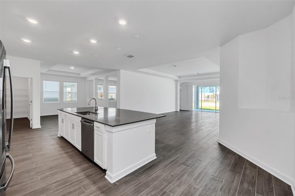 A kitchen with a dark island countertop and white cabinets overlooks an open living area — 5768 STEPHENS ROAD, ST CLOUD, FL