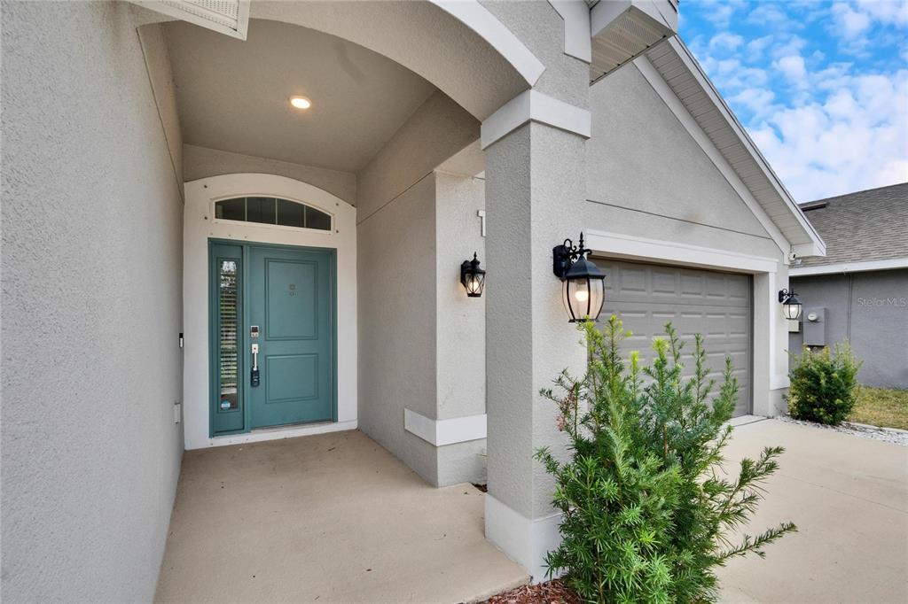 A teal front door with a sidelight is set under a covered entryway — 14525 SCOTTBURGH GLEN DRIVE, WIMAUMA, FL