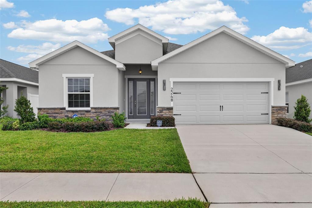 A single-story house with a gray exterior, stone accents, and a two-car garage — 2248 ORCHID DRIVE, DAVENPORT, FL