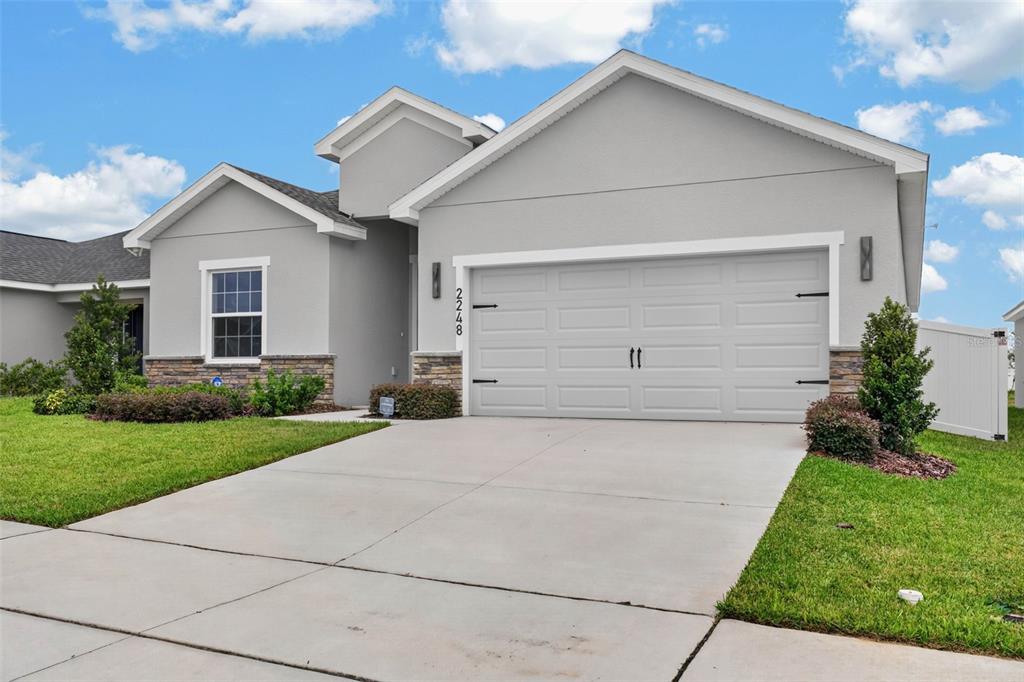 A single-story house with a gray stucco exterior, stone accents, and a two-car garage — 2248 ORCHID DRIVE, DAVENPORT, FL