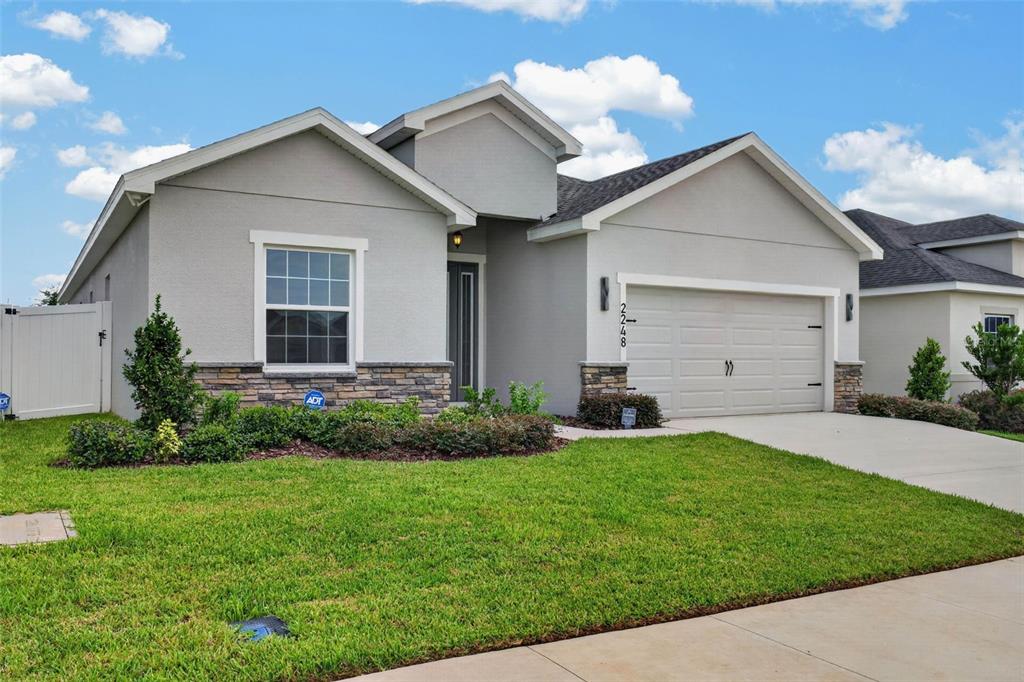 A single-story house with a gray stucco exterior, stone accents, and a two-car garage — 2248 ORCHID DRIVE, DAVENPORT, FL