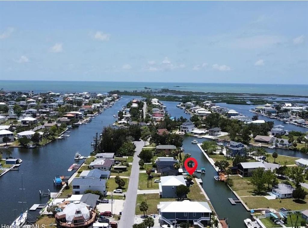 An aerial view shows a waterfront house with a red pin on a canal — 4977 CEDARBROOK LANE, HERNANDO BEACH, FL