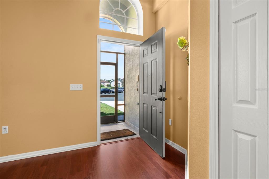 An entryway with wood flooring, a light-colored wall, and an open door leading outside — 2605 FERN COVE WAY, KISSIMMEE, FL
