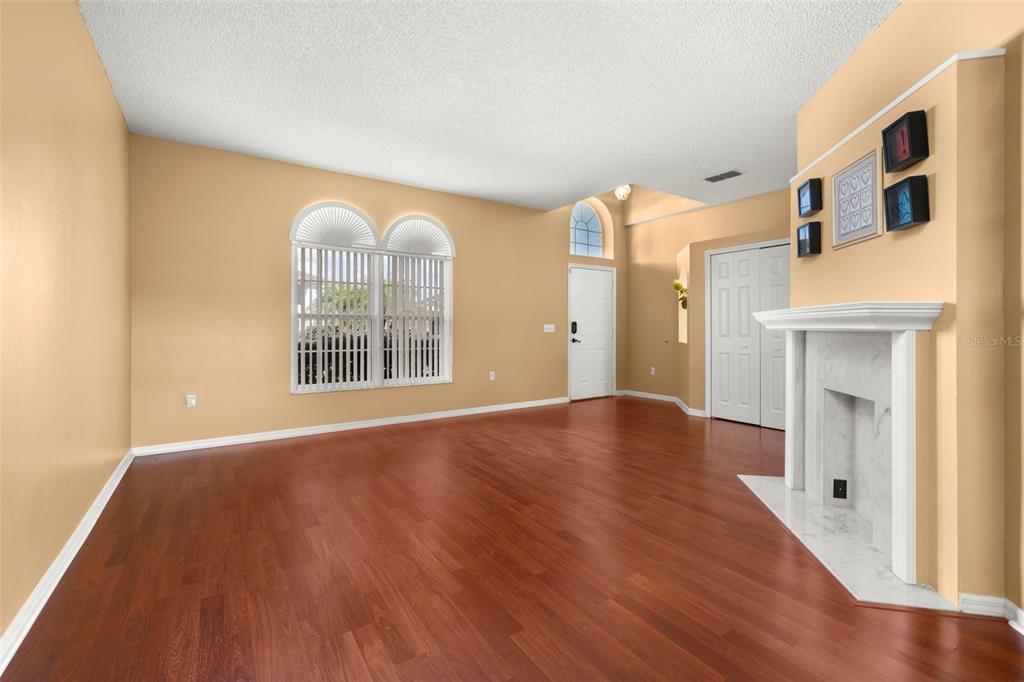 A living room with hardwood floors, a fireplace, and a large arched window — 2605 FERN COVE WAY, KISSIMMEE, FL