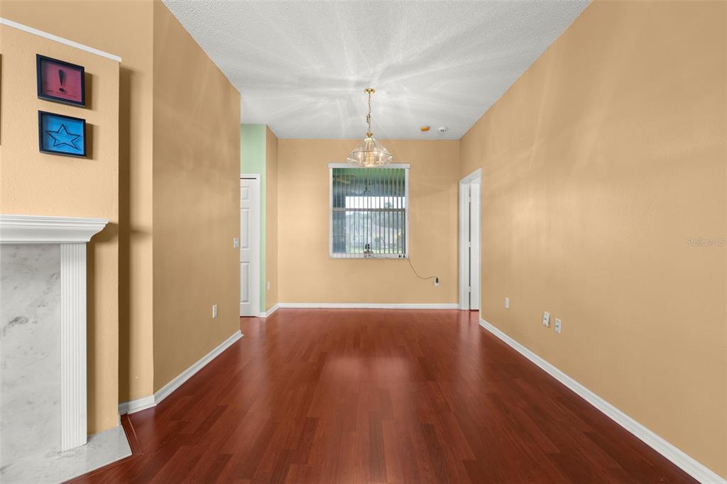 An empty dining room features hardwood floors, a central light fixture, and a window — 2605 FERN COVE WAY, KISSIMMEE, FL