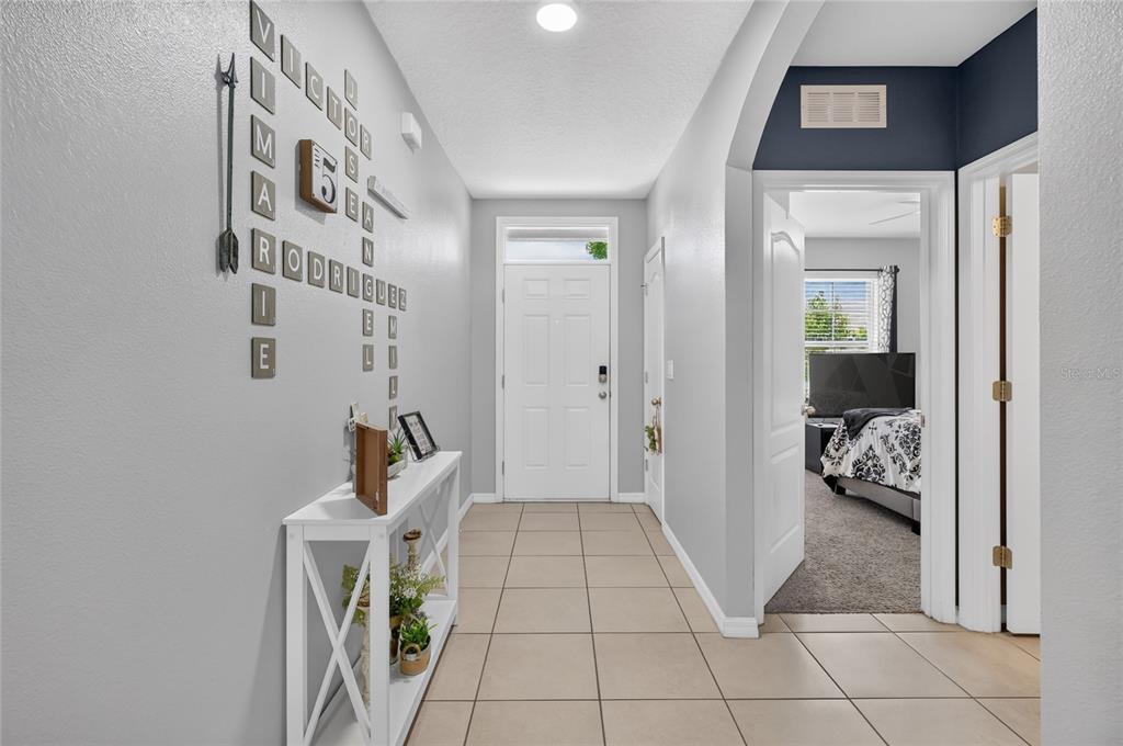 A tiled entryway features a white console table and a wall decorated with family names — 248 LUDISIA LOOP, DAVENPORT, FL