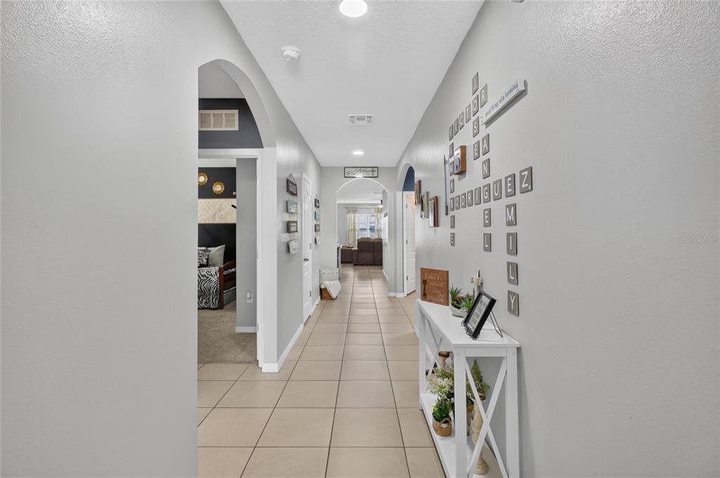 A tiled hallway leads past a white console table toward a living area in the distance — 248 LUDISIA LOOP, DAVENPORT, FL