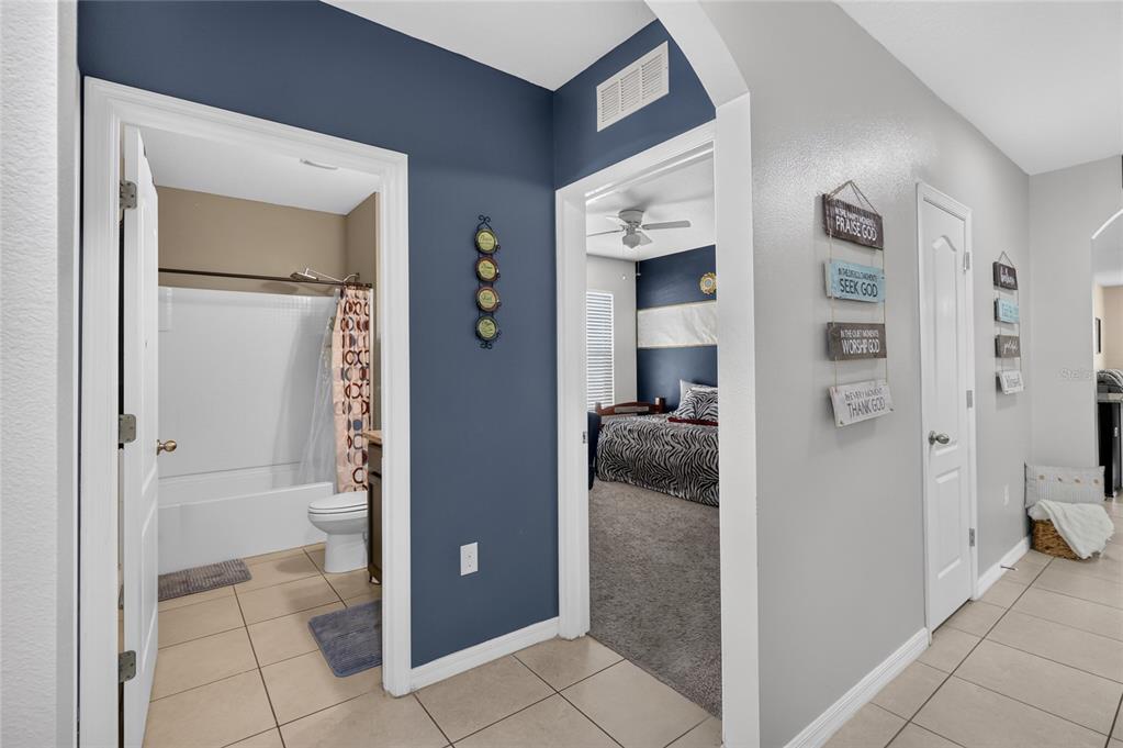 A hallway with tile flooring leads to a bathroom and a bedroom with blue walls — 248 LUDISIA LOOP, DAVENPORT, FL