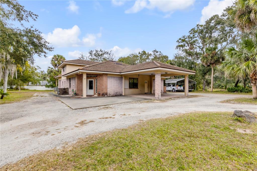 A single-story house with a brick facade, a tile roof, and a large attached carport — 12 PEARL DRIVE, ORMOND BEACH, FL