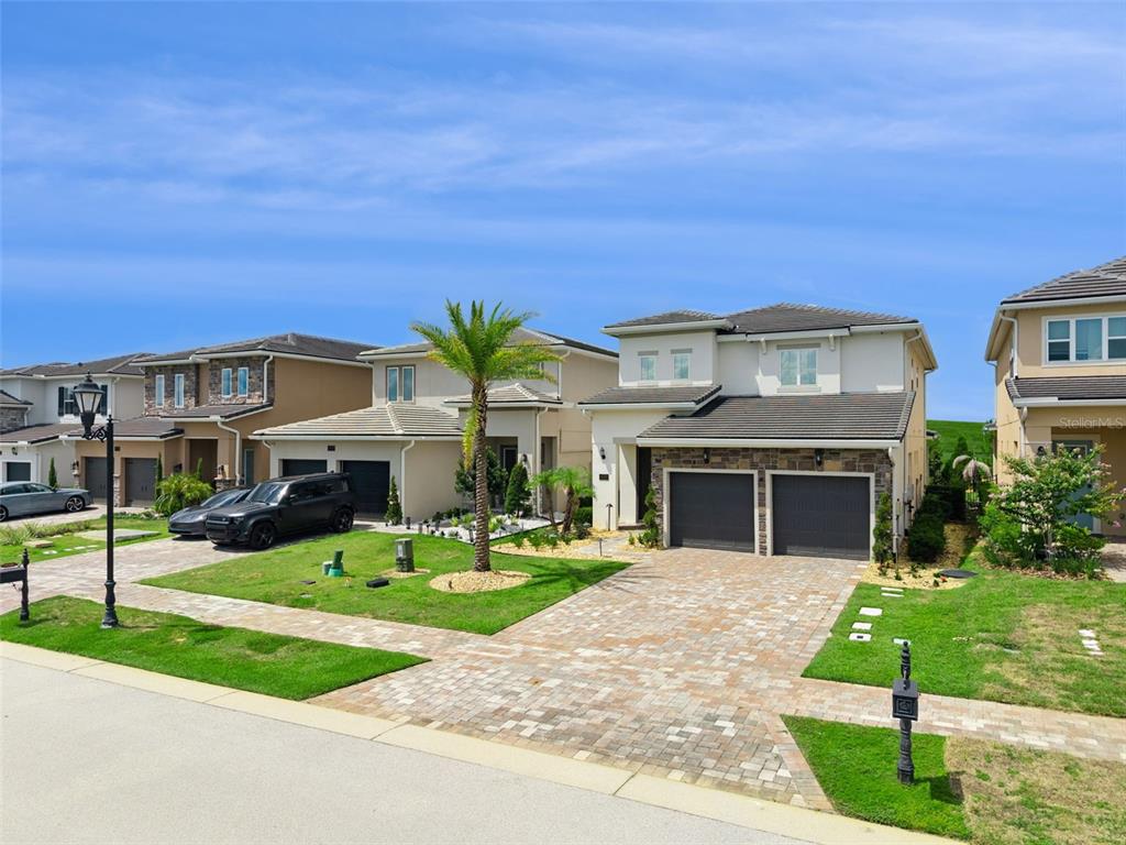 A street view of two-story suburban houses with paved driveways and green lawns — 15702 VETTA DRIVE, MONTVERDE, FL