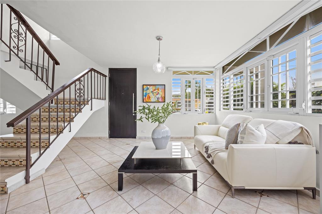 A living room features a white sofa, a two-tiered coffee table, and a tiled staircase — Calle 6 H17 TINTILLO GARDENS, GUAYNABO, PR