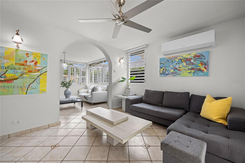 A living room features a grey sectional sofa, a coffee table, and an arched entryway — Calle 6 H17 TINTILLO GARDENS, GUAYNABO, PR