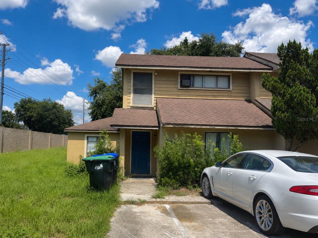 A two-story tan house with a dark blue front door and a green trash bin — 1299 WOODMAN WAY UNIT 1, ORLANDO, FL