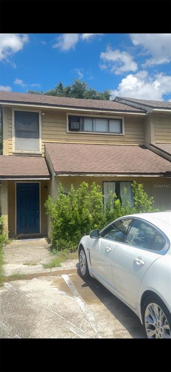A two-story tan townhouse with a blue front door and a white car parked outside — 1299 WOODMAN WAY UNIT 1, ORLANDO, FL